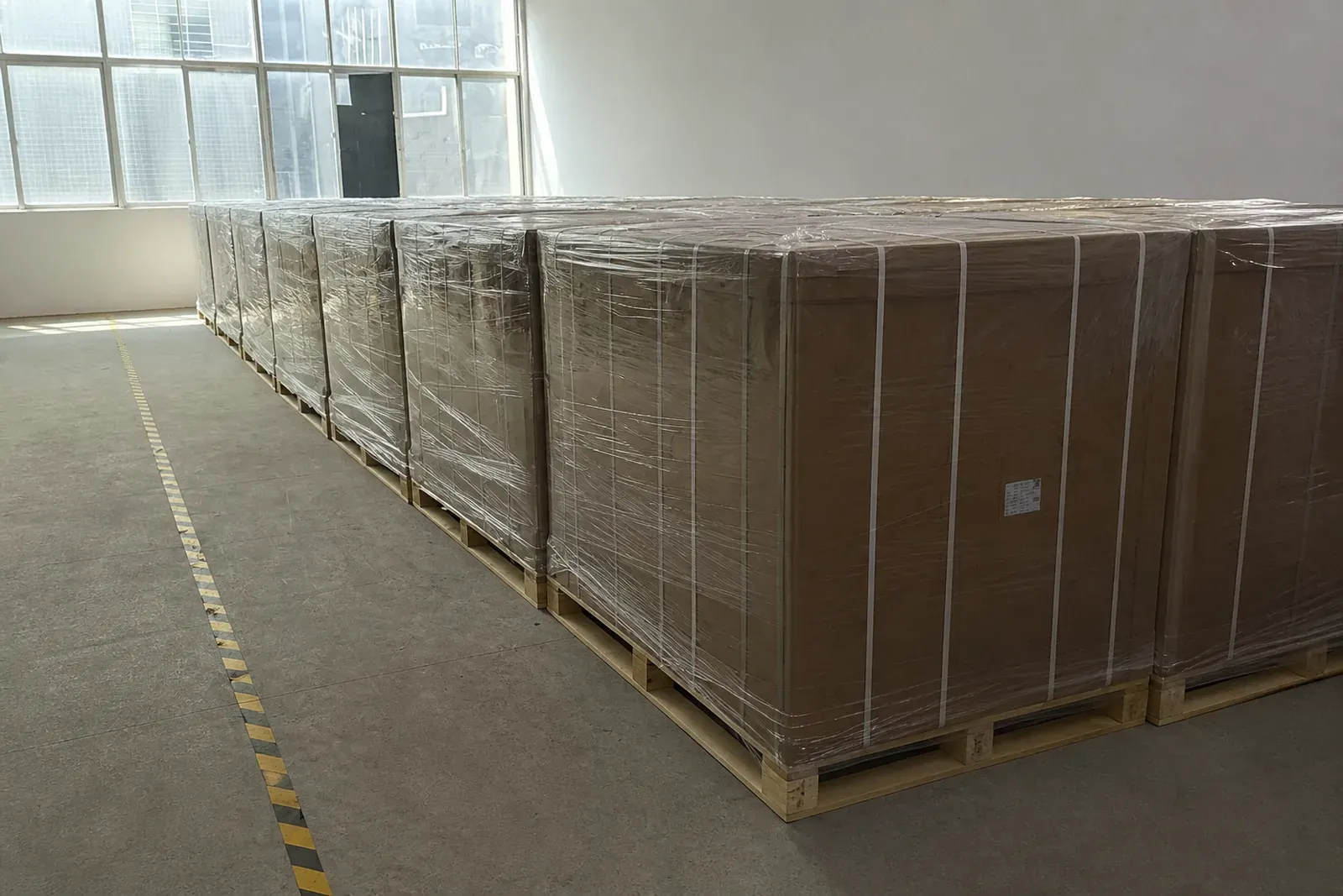 Heavy-duty export shipping containers wrapped in protective stretch film on warehouse pallets